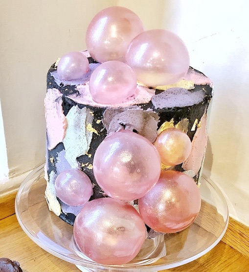 Black cake with pastels and pink bubbles, London